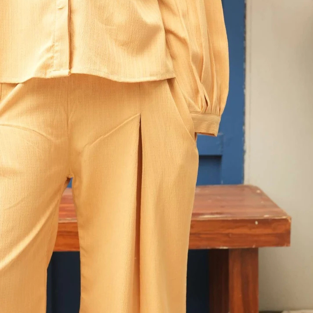 Close-up of the sandy yellow co-ord shirt hem and matching trousers