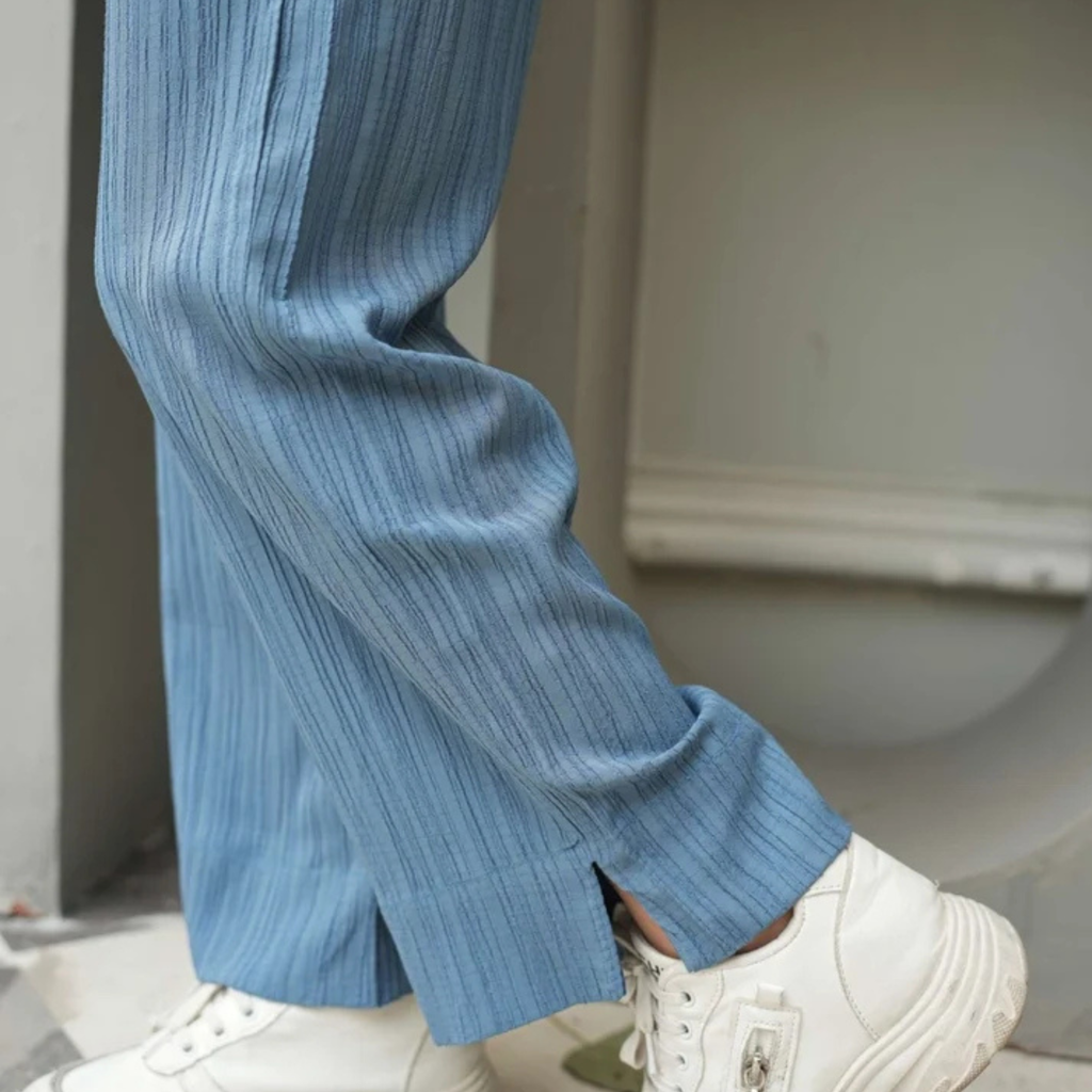 Close-up of the dusty blue wide-leg trousers and textured fabric