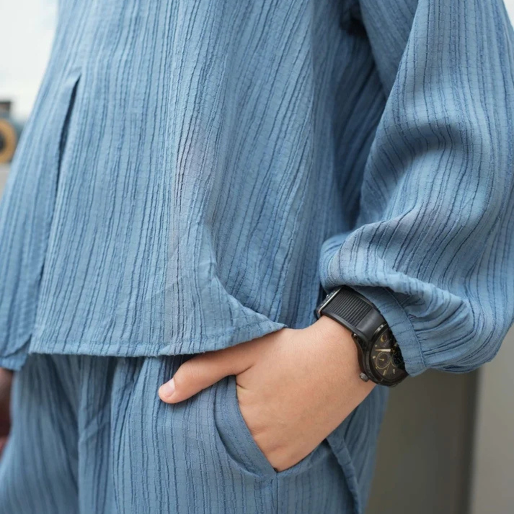 Close-up of the dusty blue co-ord shirt sleeve, hem and trouser pocket