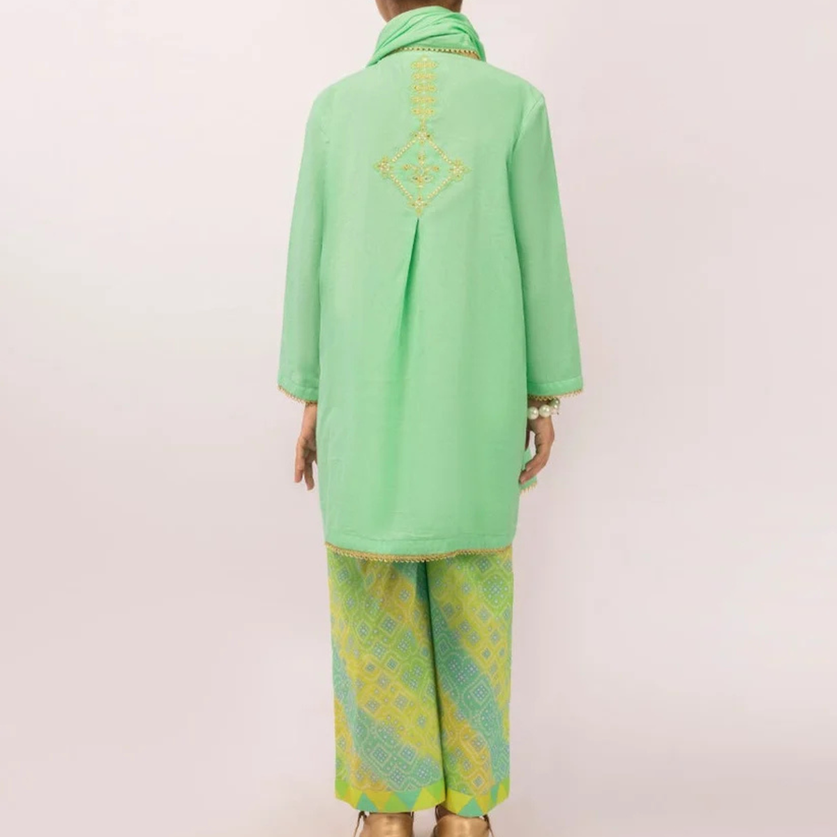 Back view of the green girls’ kurta showing the embroidered motif and patterned trousers